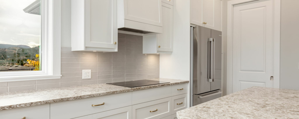 A modern kitchen featuring white cabinets and a sleek marble countertop, creating a bright and elegant cooking space.