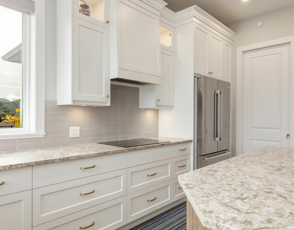 A modern kitchen featuring white cabinets and a sleek marble countertop, creating a bright and elegant cooking space.