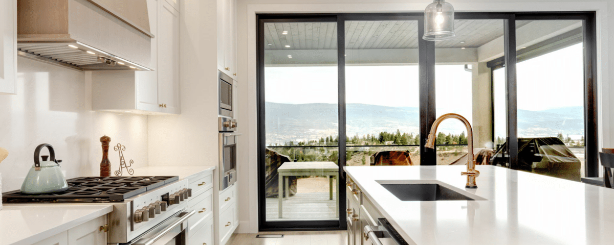 A modern kitchen featuring a spacious island and large windows offering a scenic view of the outdoors.