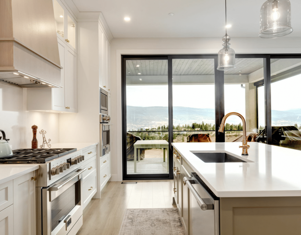 A modern kitchen featuring a spacious island and large windows offering a scenic view of the outdoors.