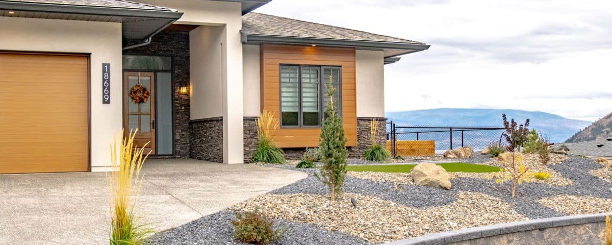 A house featuring a stone wall and well-maintained landscaping, showcasing a blend of natural and architectural beauty.