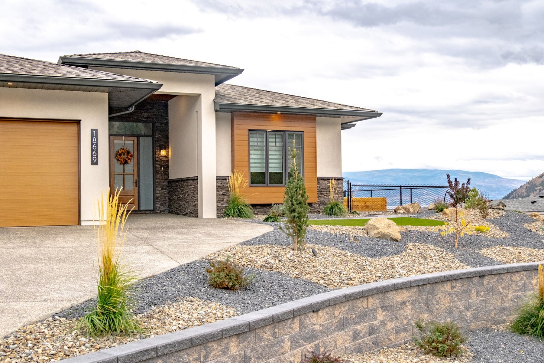 A house featuring a stone wall and well-maintained landscaping, showcasing a blend of natural and architectural beauty.