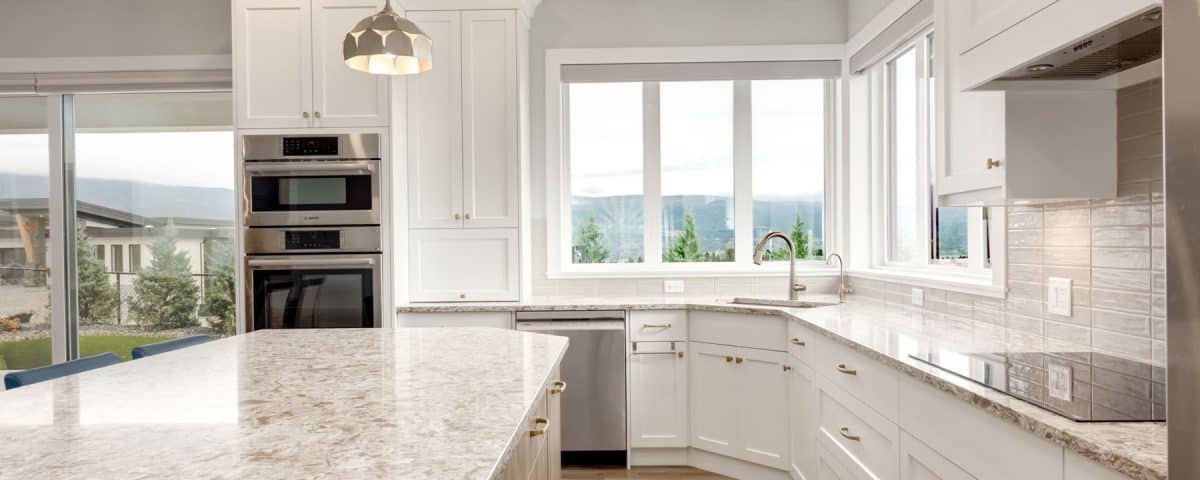 A clean kitchen featuring white cabinets and elegant granite countertops, showcasing a modern and organized space.